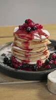 The pancakes, piled high with blueberries and cranberries, are dripping with a sweet and juicy jam. video
