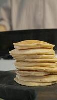 The air is filled with the aroma of freshly cooked American pancakes, emanating from a pile of them. video