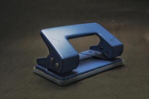 blue paper punch with black background, office stationery photo