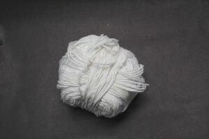 ball roll of white thread for sewing and knitting on black background photo