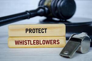 Protect Whistleblowers text on wooden blocks with whistle and lawyer gavel background photo