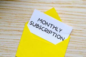 Monthly Subscription text on white notepad inside a yellow envelope. Online marketing concept photo