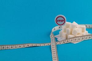 Sugar cubes with a stop sign and measuring tape on a blue background photo