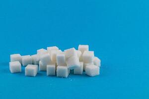 Cubes of white sugar stacked on a bright blue background photo