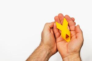 Support for cancer awareness through. a yellow ribbon held in hands photo