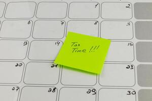Reminder note for tax deadline on calendar with empty boxes photo