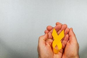 Hope and support symbol expressed through yellow ribbon held in caring hands photo