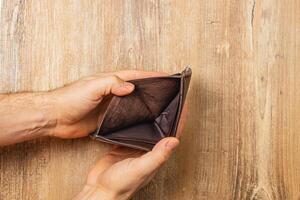 Struggling businessman examines empty wallet while facing financial crisis photo