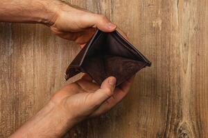 Man holds empty wallet while facing financial crisis and uncertainty photo