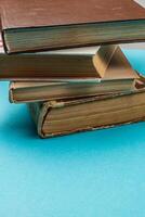 Old books stacked on a blue background creating a calm reading vibe photo