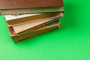 Stacked books with colorful pages on vibrant green surface photo