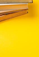 Stacked old books on a bright yellow surface for a vibrant study atmosphere photo