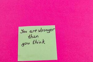 Inspirational message on a sticky note against a vibrant pink background photo