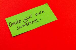 Create your own sunshine message on a bright green note against red background photo
