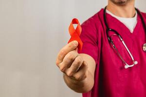 Medical professional holds red ribbon symbolizing HIV awareness during event photo