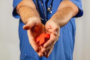 Healthcare professional holding a red healthcare symbol in hands photo