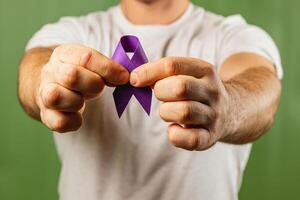Man holds purple ribbon for awareness campaign in a bright setting photo
