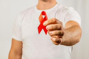 Man holding a red ribbon to raise awareness for AIDS prevention and support photo