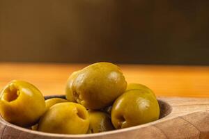 Fresh green olives arranged in a wooden bowl on a kitchen table photo
