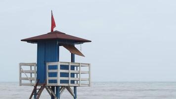 Beach guard stand with red flag on a bad weather day video