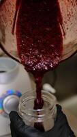 Blackcurrant puree is poured from a blender jar into a glass jar for storage smooth texture rich color fresh natural flavors artisanal preparation perfect for desserts beverages or recipes. video