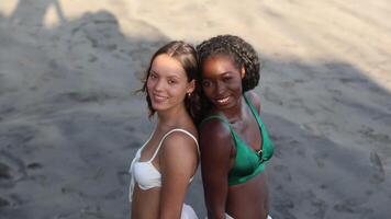 Two friends pose back to back at the seaside during vacation, girls of different ethnicities video