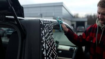 A professional car cleaner meticulously washing a shiny vehicle using a pressure hose and foam. The man focuses on the car's exterior, ensuring a spotless, polished finish at an auto detailing station video