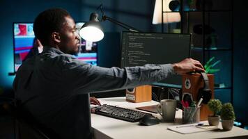 African american male programmer working on cloud computing with an algorithm, writing code for optimization on terminal window. IT specialist inserts html code, server security. Camera B. video