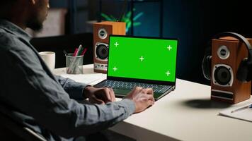 Teleworker at home editing documents next to mockup on his laptop, submitting reports and files before deadline. Black freelancer managing digital paperwork within the work platform. Camera B. video