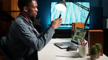 Independent adult teleworking from home and using his mobile phone, navigating social media and answering emails before starting his daily tasks completion. Comfortable modern setup. Camera B. video