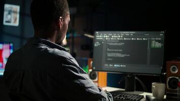 Black man programmer manages code and scripts in artificial intelligence and machine learning on dual monitors computer setup. Male freelancer uses pc to guarantee cyber security. Camera A. video