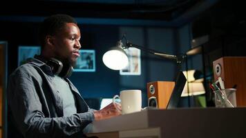African american guy does remote work and engaging in a web conversation, using his laptop to attend an online call meeting in his living room. Young man joining a conference. Camera A. video