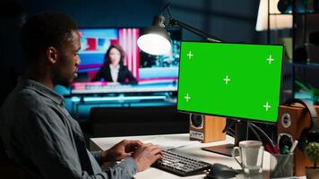 African american adult working from home using chroma key mockup, reviewing statistical data to compare supply and demand numbers. Sitting at desk and writing on his computer. Camera B. video