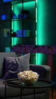Vertical Contemporary living space with remote control and snacks on table reflecting preparation for movie night, panning shot. Close up of popcorn bowl in apartment with relaxing atmosphere video