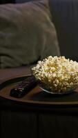 vertical cuenco de palomitas de maiz en café mesa en frente de acogedor sofá en vacío neón iluminado moderno departamento. cerca arriba Disparo de bocadillo preparado para película noche en hogar teatro usado para entretenimiento sesiones video