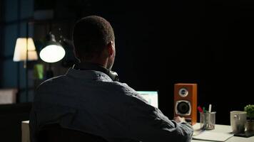 African american analyst works on accounting analysis while he is dancing, feeling the rhythm and checks financial balance. Remote worker listening to favorite groovy music on headphones. Camera A. video