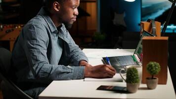 se stesso occupato nero uomo multitasking a casa assunzione manoscritto Appunti e navigazione il ragnatela per progetto ricerca. gestione programma e compiti con un' progettista per Incremento produttività. telecamera b. video