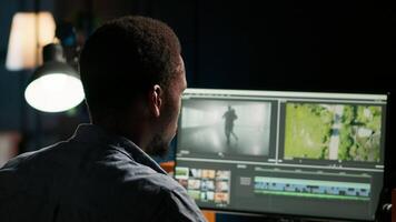 Black guy editor working with dual monitors for creative content, editing footage and does color grading for the media creation. Male professional works in post production. Camera B. video
