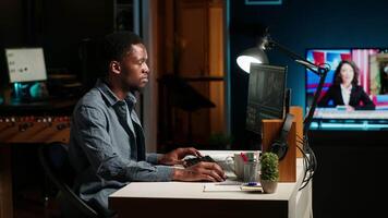 Focused male editor working on montage in a creative software at home office setup, digital media content. Filmmaker using dual monitors to edit footage in post production. Camera B. video