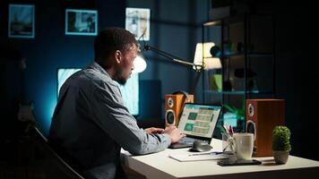 Focused remote worker balancing freelance tasks and researching data online, drafting notes and information for articles. Black person working at home, planning schedule and projects. Camera A. video
