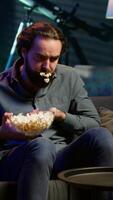 Vertical Man in apartment chocking on food while watching movie on TV and eating popcorn. Person getting throat clogged while swallowing snack, doing heimlich maneuver on couch, fighting for his life, camera A video