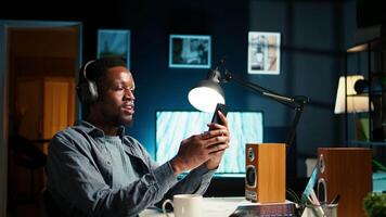 African american man waving and attending a web meeting from his urban apartment. Engaged male freelancer discussing work remotely with coworkers using wireless for conferencing call. Camera A. video