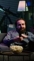 Vertical Excited man throwing himself on couch, rushing to catch start of favorite TV show episode. Enthusiastic person in a hurry to watch television series jumping on couch at home, camera A video