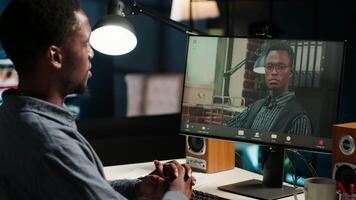 African American man enjoys conferencing with manager at desk, discussing with his colleague online using a computer at home office setup. Young associates team meeting online. Camera B. video