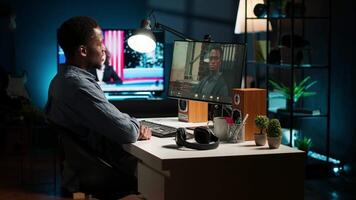 Black remote worker meeting with his team leader via conference call, sharing ideas and insight on his tasks from his home office setup. Young adult joining web chat with boss. Camera B. video