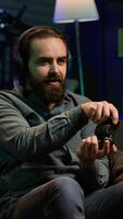 Vertical Gamer wearing headphones frustrated after getting game over message while playing videogame, raging. Man gaming with controller at home angry after losing level, camera A video