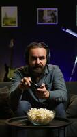 Vertical Man looking in disbelief at TV screen while playing videogames, receiving game over message on gaming console. Gamer upset after being defeated by rival players in online esports competition, camera B video