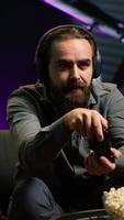 Vertical Man looking in disbelief at TV screen while playing videogames, receiving game over message on gaming console. Gamer upset after being defeated by rival players in online esports competition, camera A video