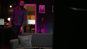 Happy person arriving home, excited to do gaming during leisure time. Cheerful player entering room, jumping on couch, excited to play videogame on console, relaxing after hard day at work video
