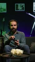 Vertical Satisfied gamer bragging after finally defeating all enemies while playing on gaming console. Pleased player congratulating himself after winning videogame using controller, camera B video